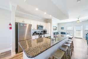 A modern kitchen with a granite countertop, stainless steel appliances, and a bar area with stools.