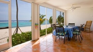 Un espace repas avec vue sur la plage, de grandes fenêtres et un ventilateur de plafond.