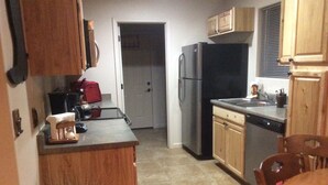 A compact kitchen with wooden cabinets, a black refrigerator, a sink, and a dining table with chairs. -   Casita 3 blocks from downtown!  Very clean ! (Wickenburg)