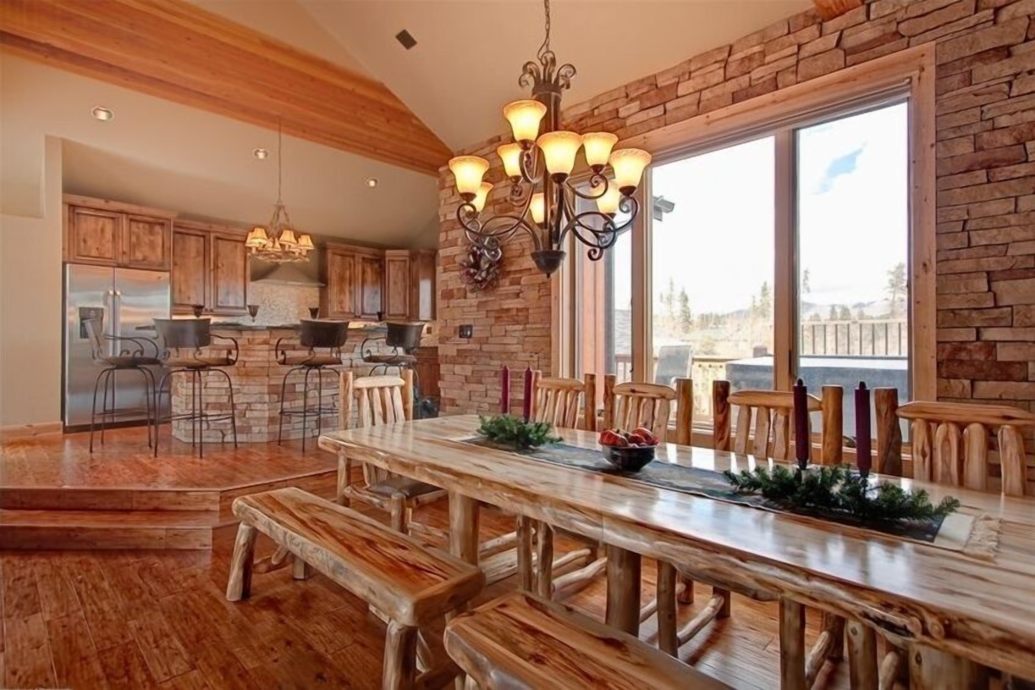 A spacious kitchen with wooden cabinets, a large dining table, and a stone accent wall.