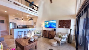 A spacious living area with a kitchen, a dining area, and a high ceiling with exposed beams. - Direct Oceanfront Condo with Amazing Island Views!! (Lahaina)