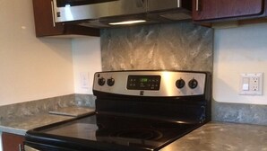 Una cocina con horno de acero inoxidable, un microondas encima y una encimera de granito.
