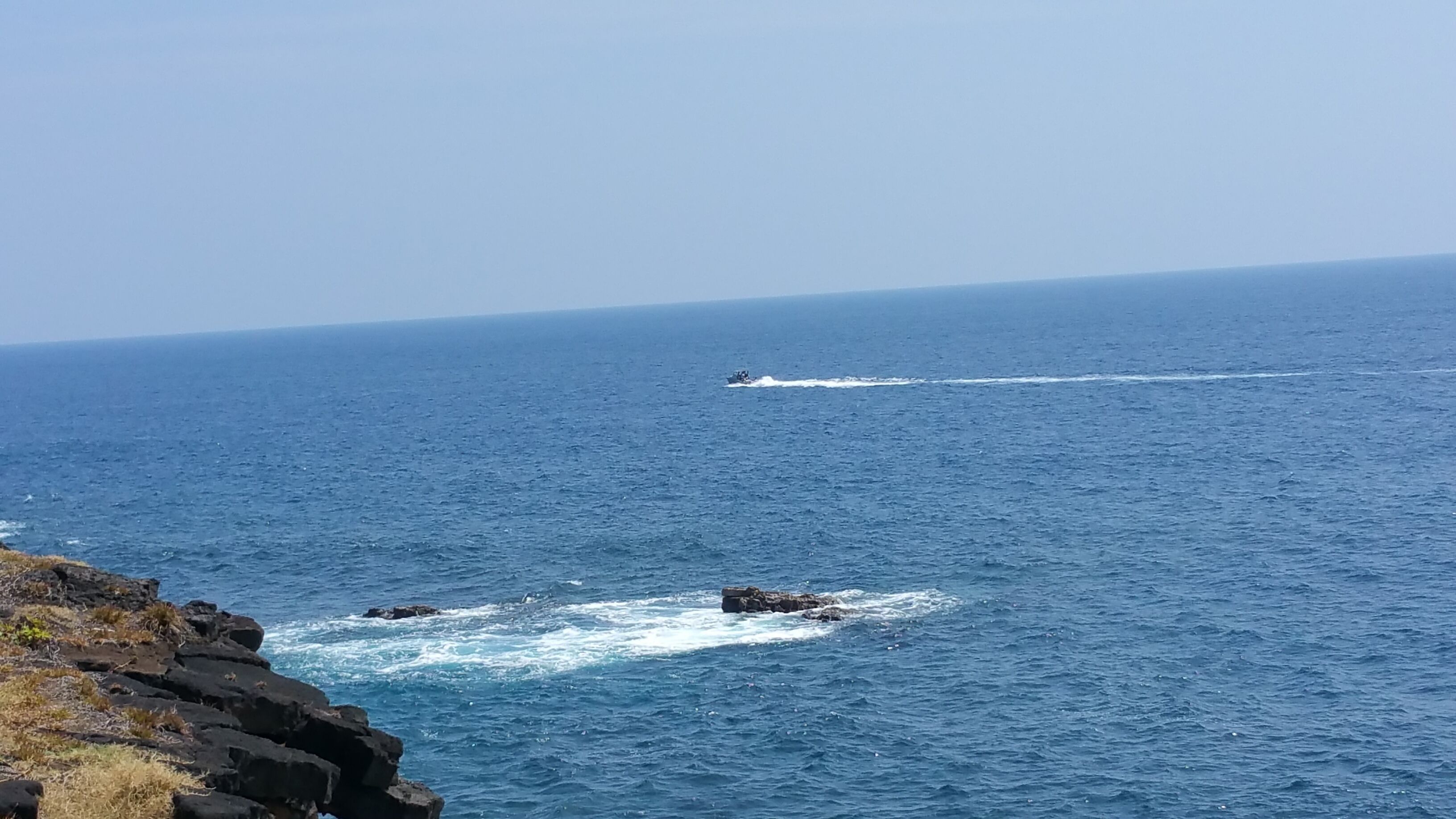 A coastal scene with a clear view of the ocean and rocky shoreline.