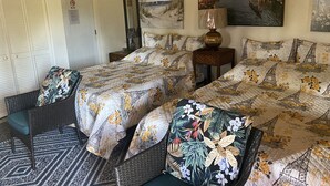 A double bed with floral and Eiffel Tower themed bedding, a nightstand with a lamp, a wicker chair, and a patterned rug. - Nice Studio w/ A/C Near Kehena/Pohoiki Beaches and Lava Fields - sleeps 3 (Pahoa)
