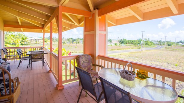 A covered porch with wooden flooring, a glass table, and several chairs. - Nice Studio w/ A/C Near Kehena/Pohoiki Beaches and Lava Fields - sleeps 3 (Pahoa)