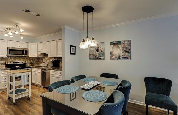 A modern kitchen with white cabinets, a microwave, stove, and a dining area with a table and chairs.