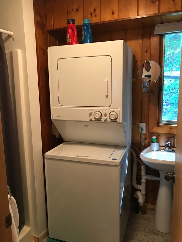 A compact laundry room with a front-loading washer and dryer, a sink, and wooden walls. - Vacation on the most exciting strip on Otter Tail Lake (Battle Lake)