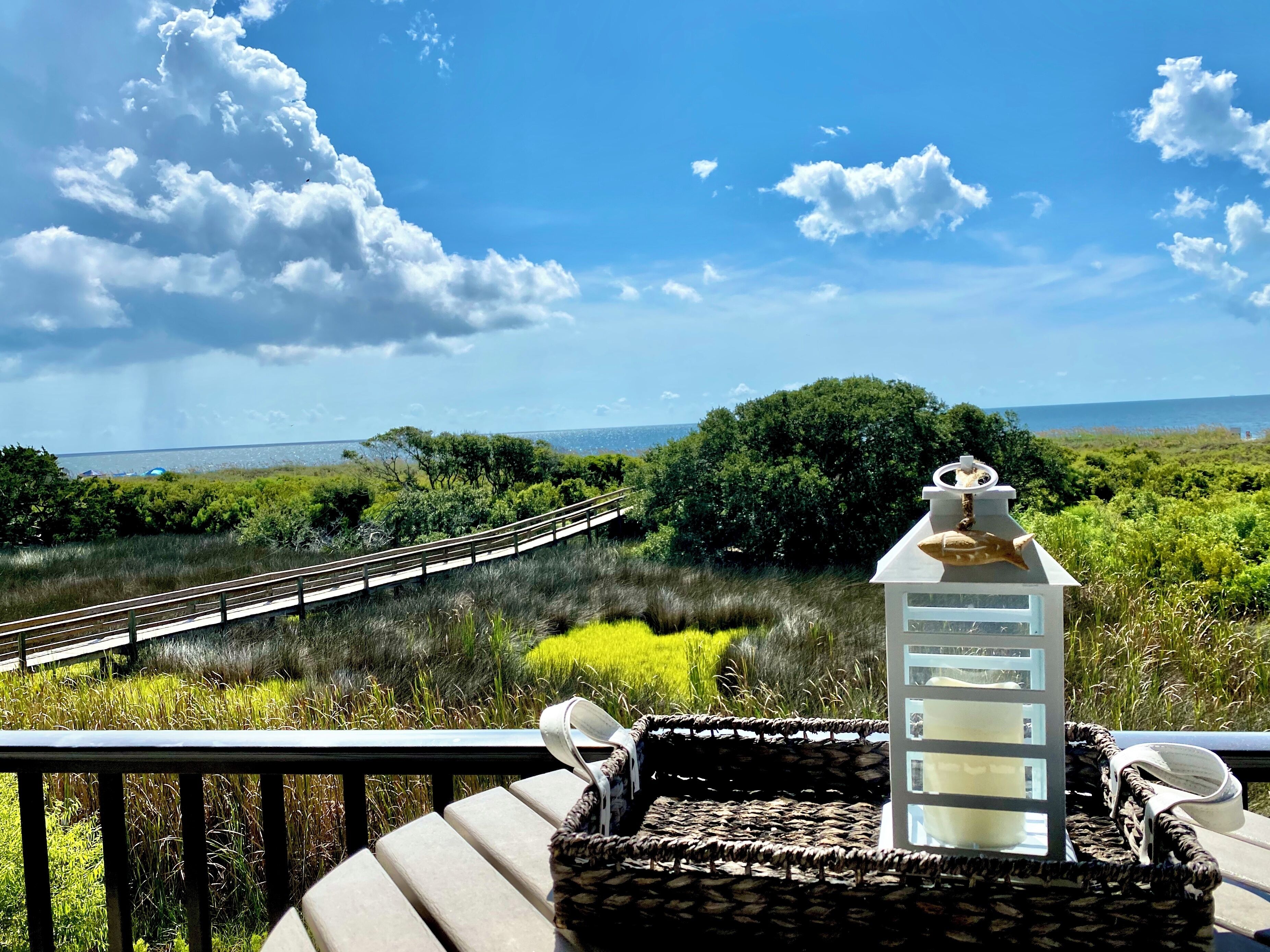 A wooden deck with a railing, a white lantern, and a wicker basket.