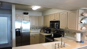 A kitchen with light-colored cabinets, stainless steel appliances, and a white countertop. - Any Closer to the Beach, You'd Have Sand in Your Sheets! After summer specials. (Miramar Beach)
