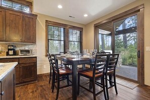 A modern kitchen with wooden cabinets, a built-in microwave, and a dining area with a table set for four. - Central Location w/ Suncadia Pool Access (Cle Elum)