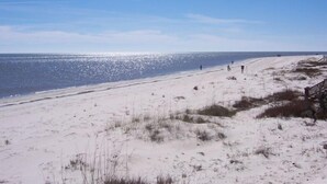 Une plage de sable avec une promenade en bois et un ciel bleu dégagé.