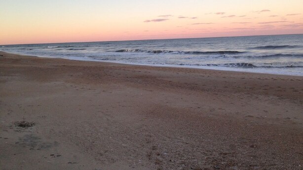 Une plage avec un ciel dégagé et une mer calme.