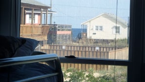 Une chambre avec une fenêtre donnant sur une terrasse en bois et une maison de plage.