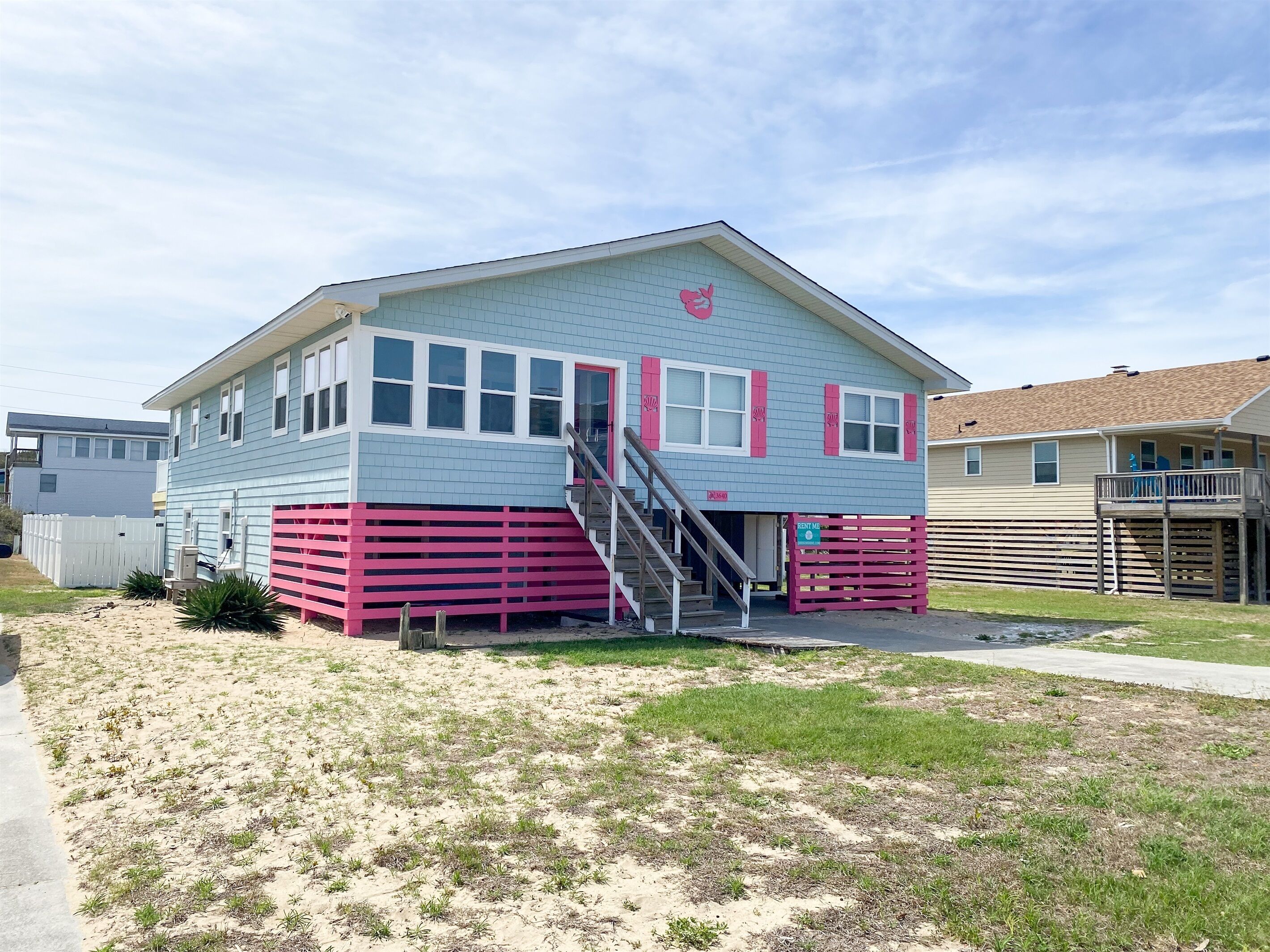 A two-story house with a pink and white exterior, a front porch, and a staircase leading to the entrance.