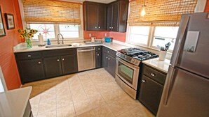 A kitchen with dark cabinets, a gas stove, a dishwasher, and a refrigerator.