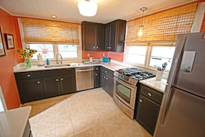 A kitchen with dark cabinets, a gas stove, a dishwasher, and a refrigerator.