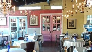 L’intérieur d’un restaurant avec des tables rondes, des chaises et des lustres.