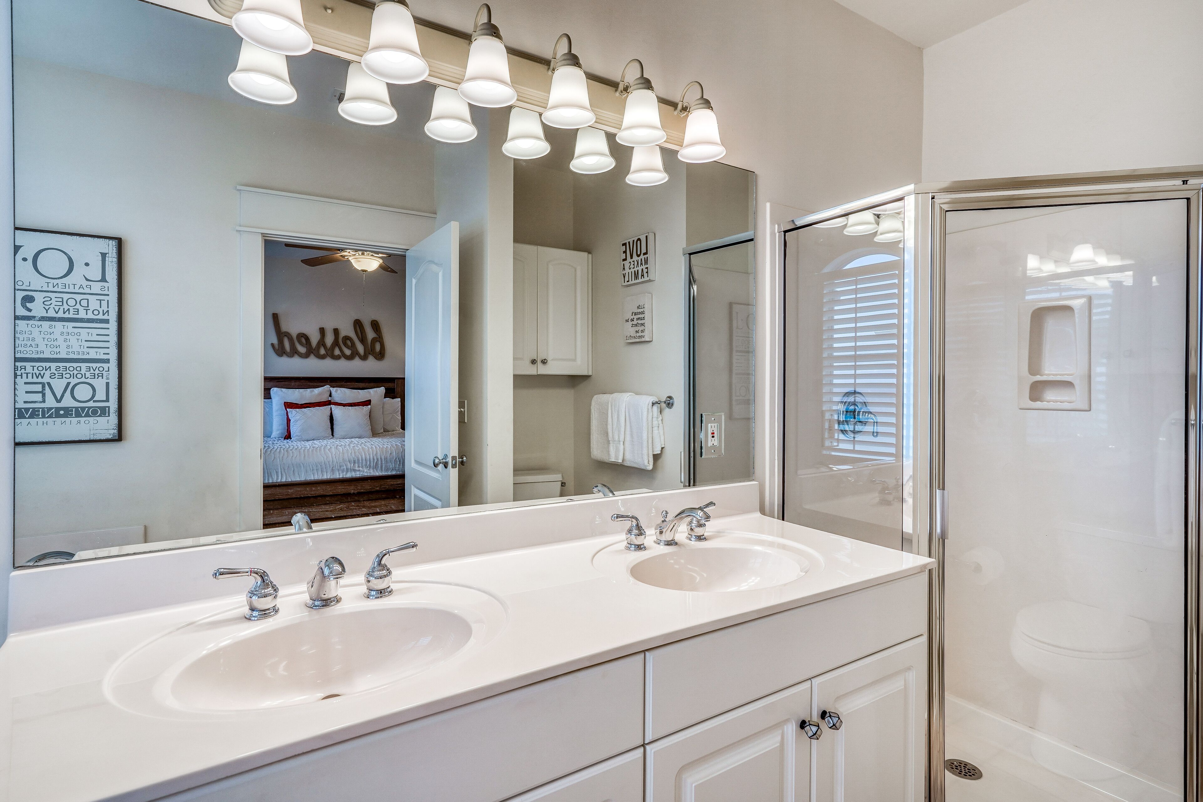A bathroom with two sinks, a large mirror, and a shower enclosure.