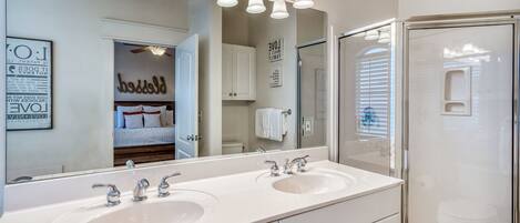 A bathroom with two sinks, a large mirror, and a shower enclosure.