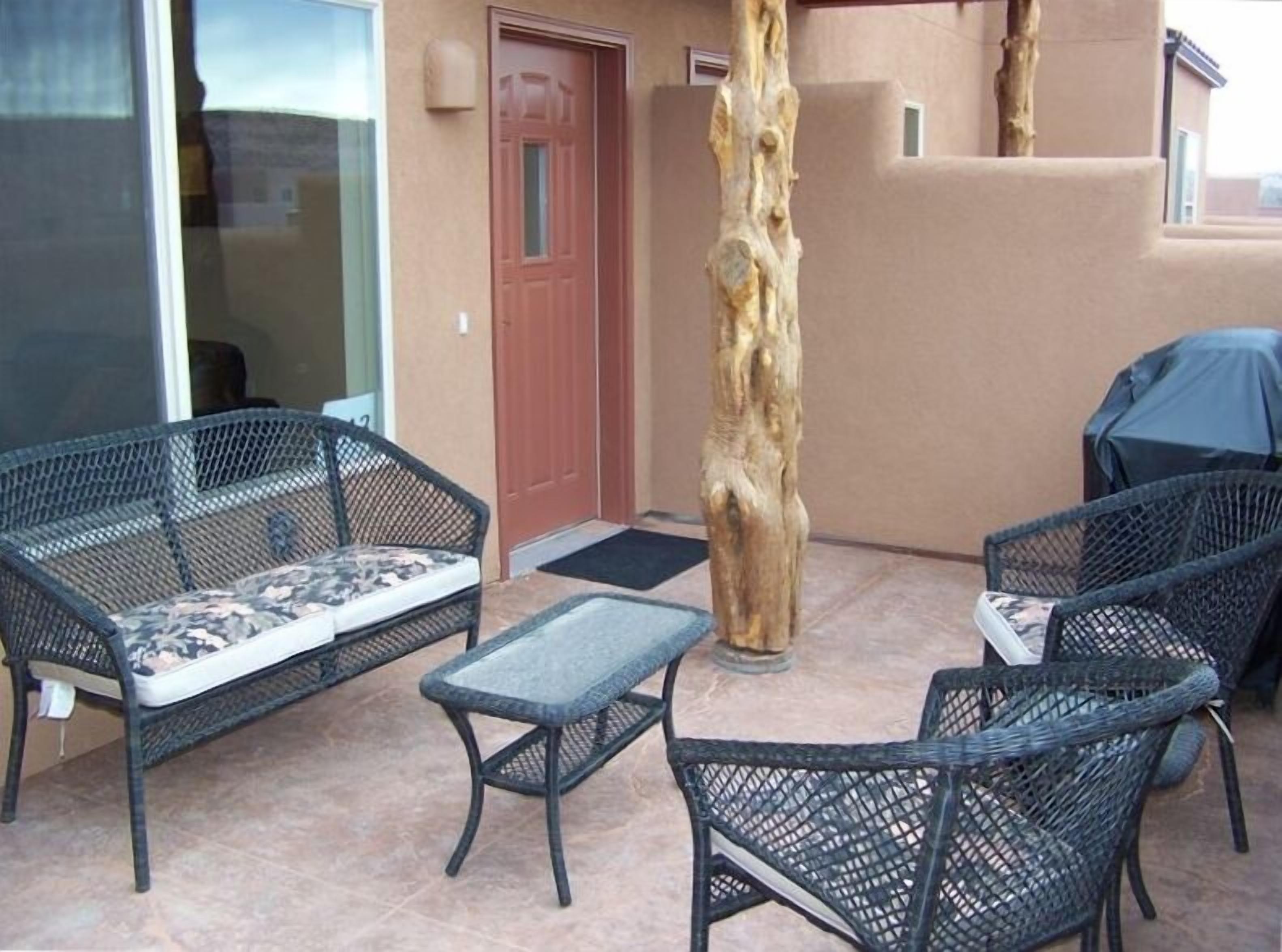 An outdoor seating area with wicker furniture and a tree trunk centerpiece.