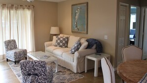 A living room with a beige sofa, patterned armchairs, a coffee table, and a painting on the wall. - Plantation Style cottage short walk to beach and town 
Permit STPH2013/0004   (Paia)