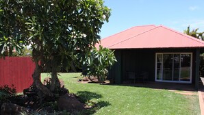 A house with a red roof, a covered patio, and a lawn. - Plantation Style cottage short walk to beach and town 
Permit STPH2013/0004   (Paia)
