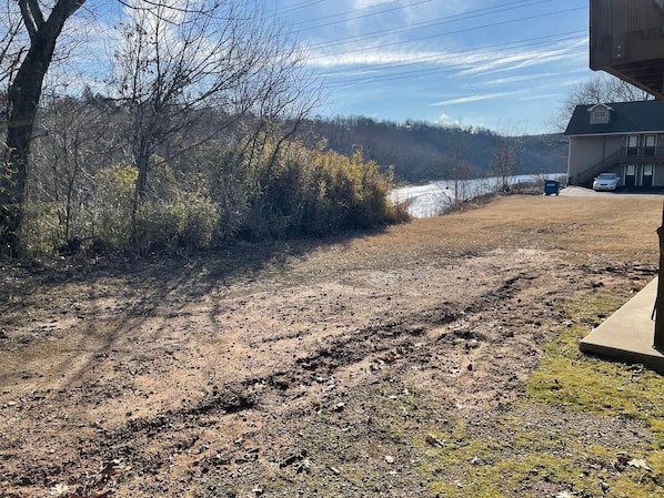 A dirt path leading to a house with a garage and a vehicle parked outside.