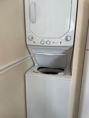 A front view of a white front-loading washing machine with control knobs and a door. - Waterfront Walk In (Branson)