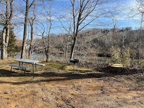 A picnic table and a mailbox in a natural setting with trees and a body of water in the background. - Waterfront Walk In (Branson)