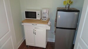 A compact kitchenette with a microwave, coffee maker, and refrigerator.