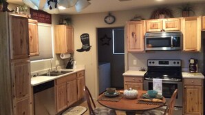 A compact kitchen with wooden cabinets, a microwave, an oven, and a dining table with chairs. -  Casita only 3 blocks from downtown- Very clean! (Wickenburg)