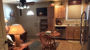 A compact kitchen with wooden cabinets, a dining table with chairs, a ceiling fan, and a refrigerator. -  Casita only 3 blocks from downtown- Very clean! (Wickenburg)