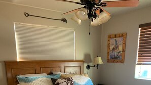 A bedroom with a bed, a ceiling fan, a window with blinds, and a wall-mounted lamp. -  Casita only 3 blocks from downtown- Very clean! (Wickenburg)