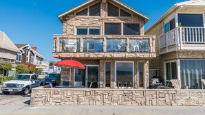 A two-story building with a stone facade, large windows, and outdoor seating.
