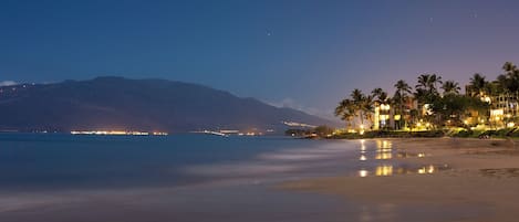 Un hôtel situé en bord de mer, offrant une vue sur l’océan et les montagnes en arrière-plan.