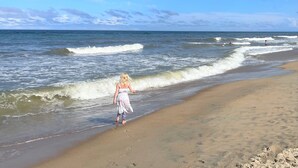 A beach with a person walking along the shore. - Perfect Getaway - 2 minute walk straight to the Beach (Kill Devil Hills)