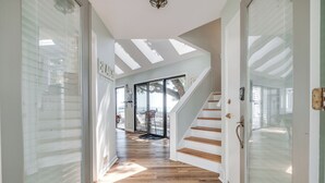 A hallway with wooden flooring, a glass door with a nameplate, and a staircase leading to an outdoor area.