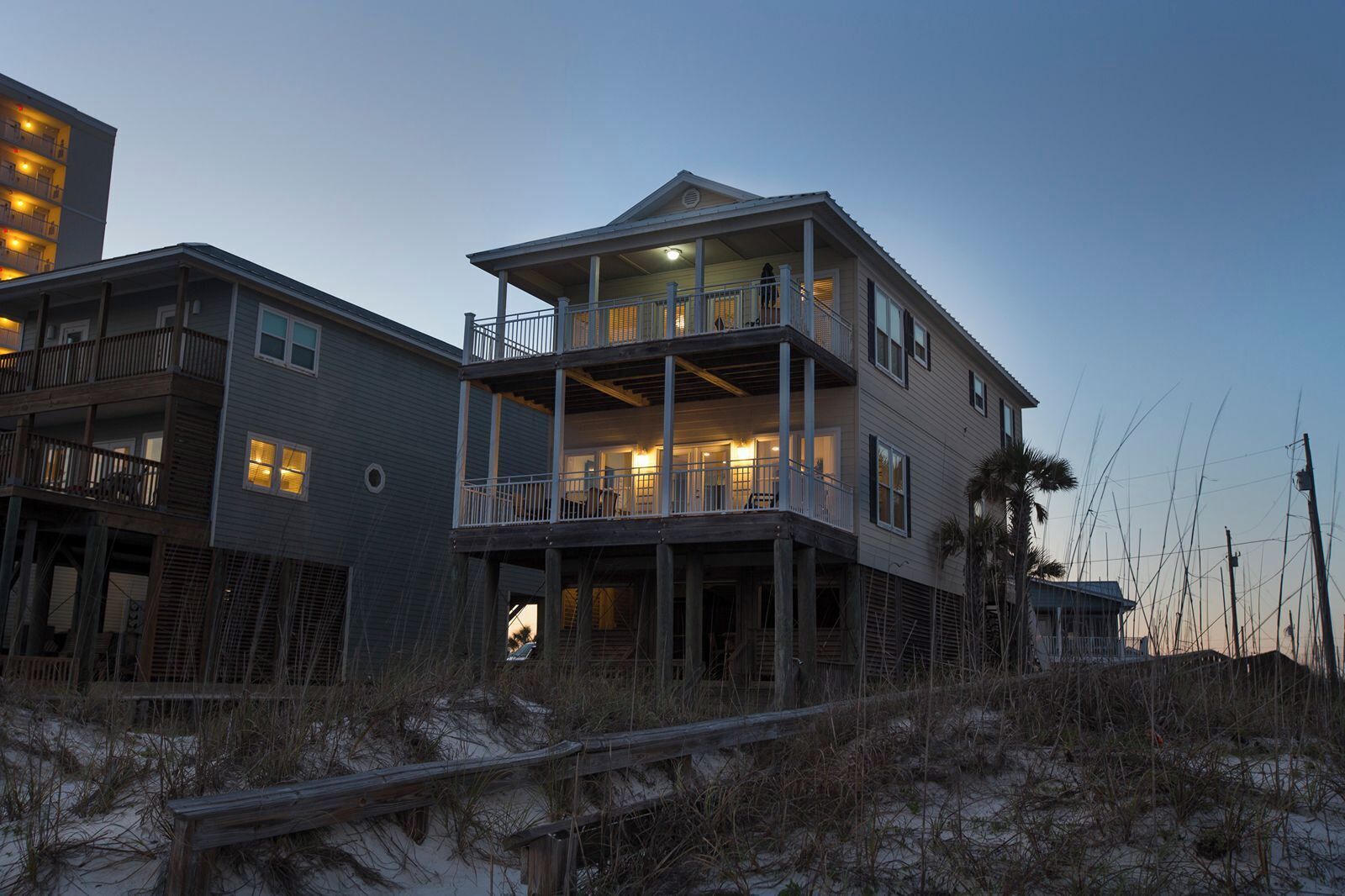 A two-story beachfront house with multiple balconies and a covered porch.