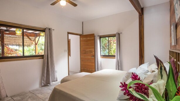 A bedroom with a bed, two windows, and a wooden ceiling.