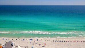 A beach with a clear view of the ocean, a sandy shore, and a row of beach umbrellas.