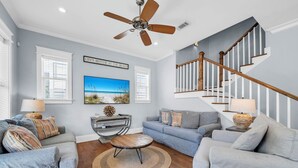 A living room with a sofa, a coffee table, a TV, and a staircase. - 2 Master Suites, 4 Bedroom,  Five ★ Home, Gourmet Kitchen - short walk to beach (Santa Rosa Beach)
