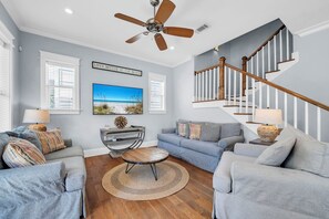 Ein Wohnzimmer mit einer Couch, einem Couchtisch, einem Fernseher und einer Treppe.