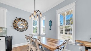 A dining area with a wooden table, white chairs, a decorative mirror, and a seahorse wall art piece. - 2 Master Suites, 4 Bedroom,  Five ★ Home, Gourmet Kitchen - short walk to beach (Santa Rosa Beach)