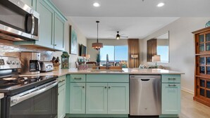 Une cuisine moderne avec des meubles de couleur turquoise, des appareils électroménagers en acier inoxydable et un lave-vaisselle.