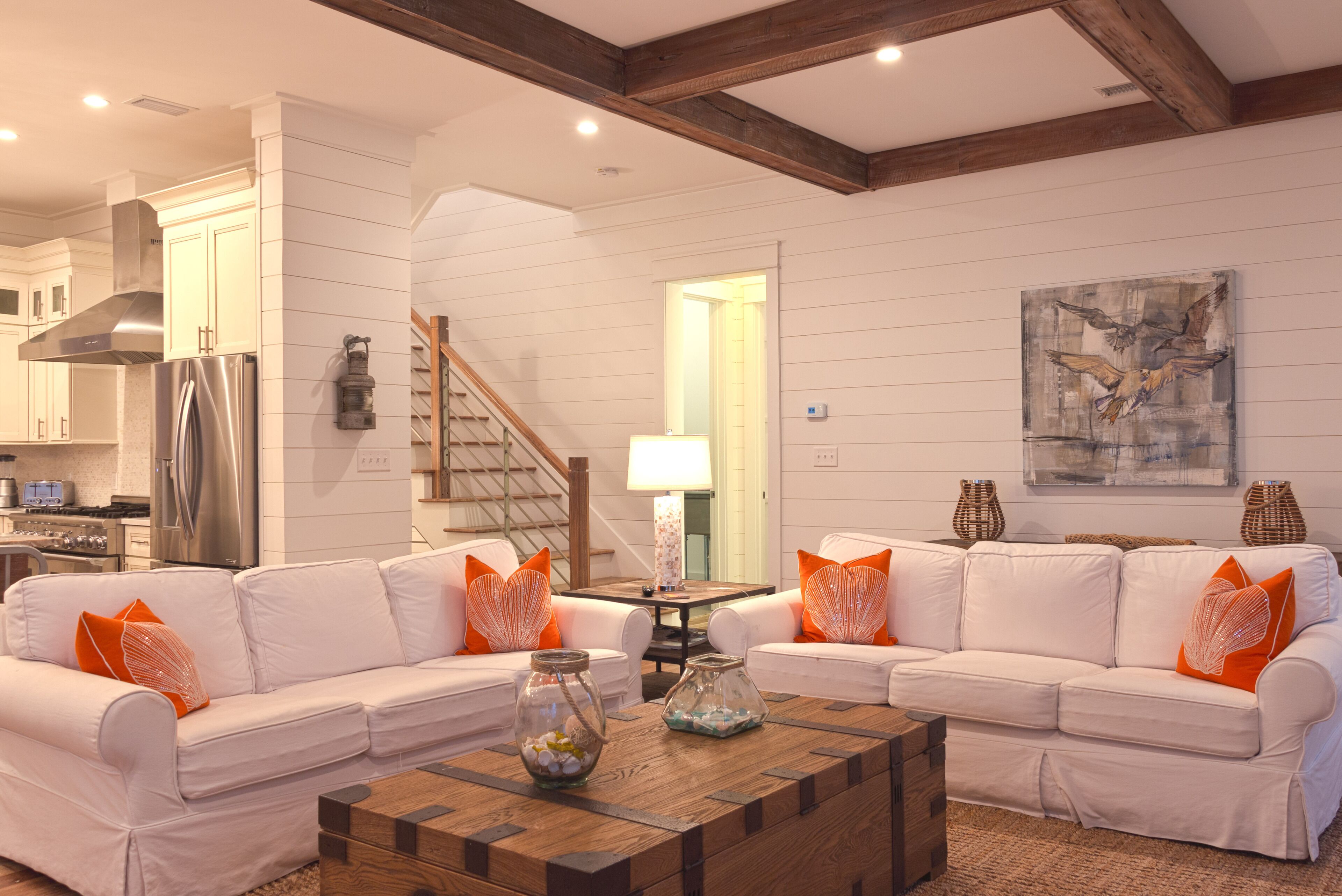 A modern living room with a white sofa set, a wooden coffee table, and decorative glass vases.