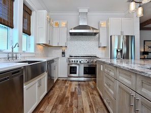 A kitchen with white cabinets, a stainless steel range, and a wood floor.