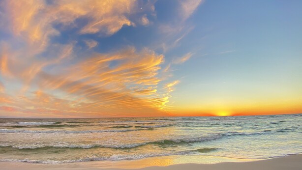 Una playa con olas y un atardecer.