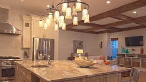 Una cocina amplia con una isla grande, electrodomésticos de acero inoxidable y techo de madera.