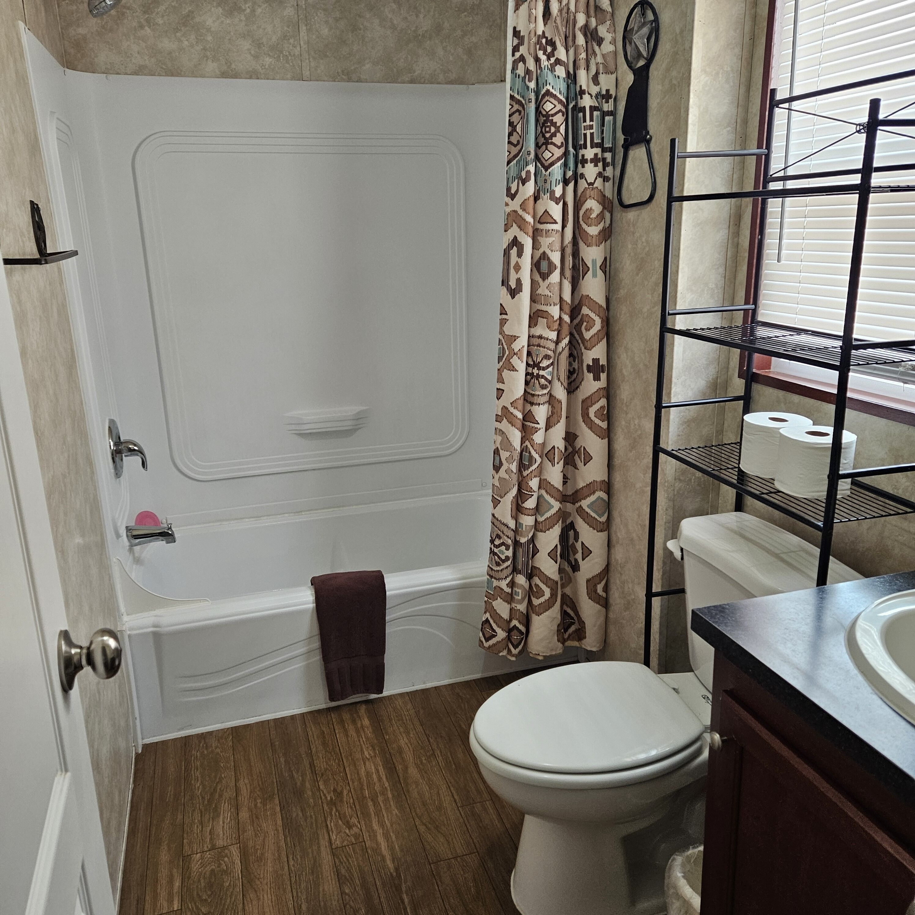Une salle de bain équipée d’une baignoire, de toilettes et d’une étagère où sont rangés les articles de toilette.