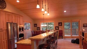 A spacious kitchen with wooden cabinets, a stainless steel refrigerator, and a granite countertop.